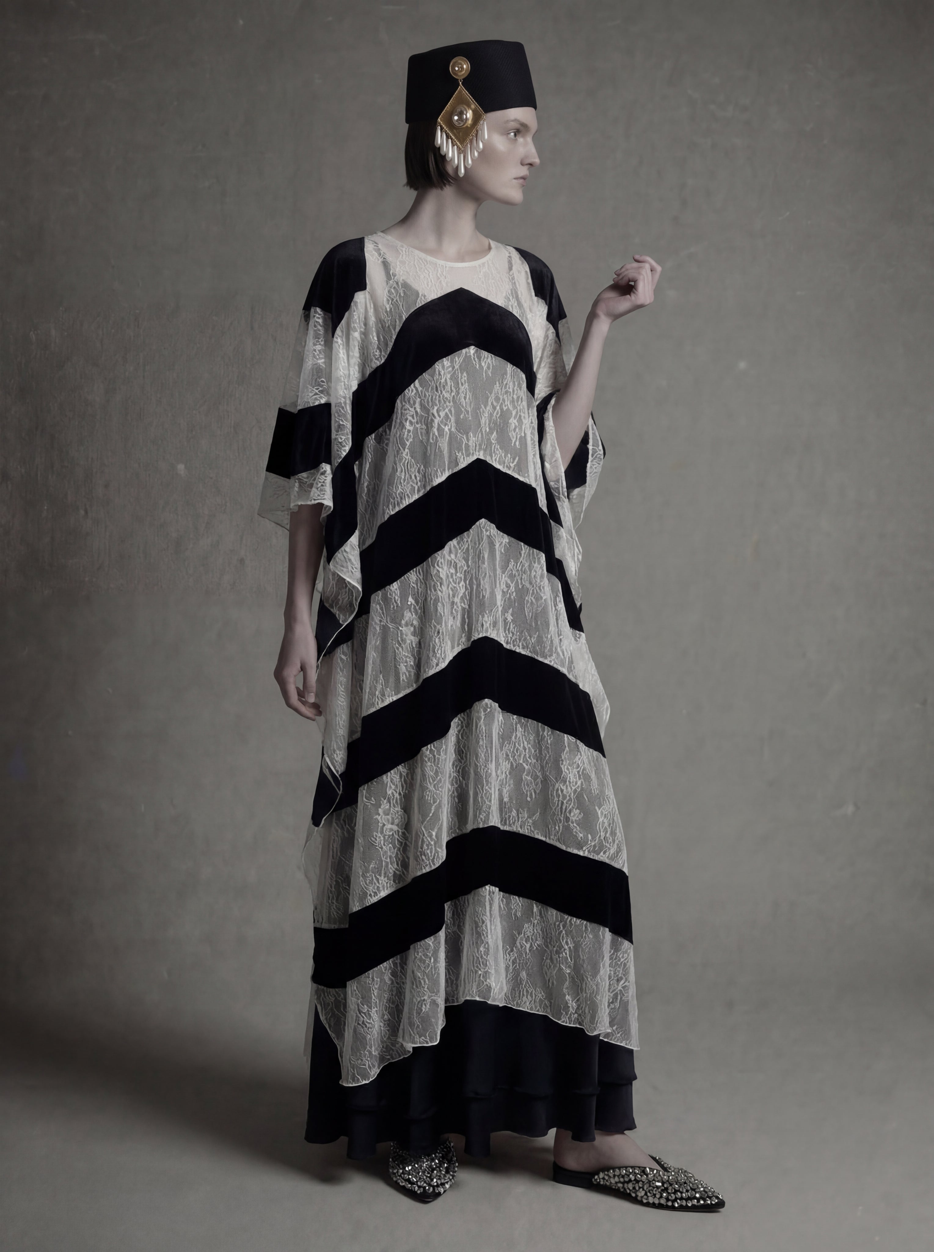 Woman wearing a black and white striped dress with a hat against a gray background